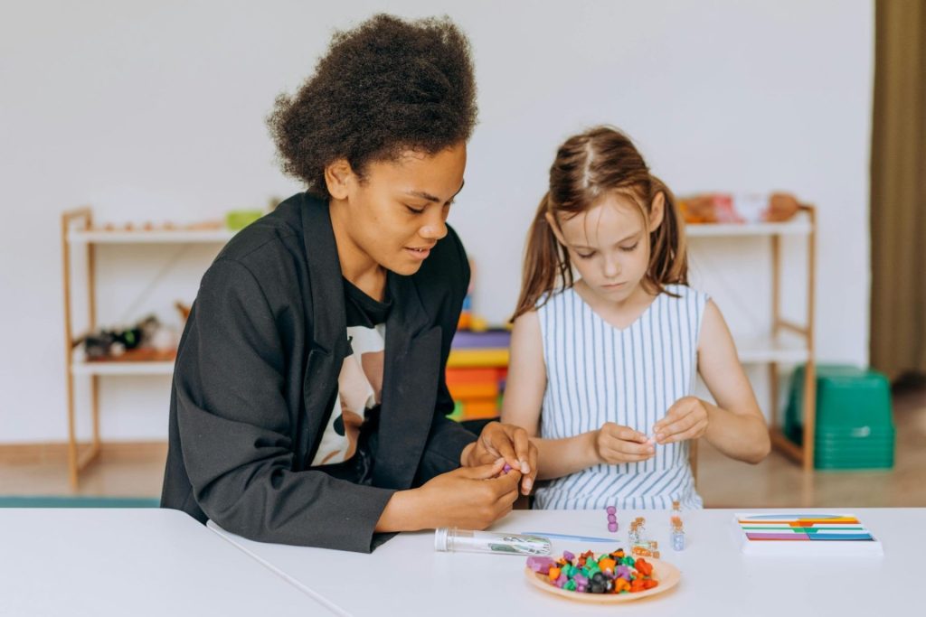 Deux personne dont un enfant lors d’une activité manuelle avec des perles colorées.