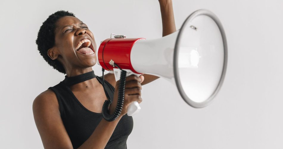 Femme criant dans un mégaphone, le poing levé, pour illustrer l’utilisation intensive de la voix.